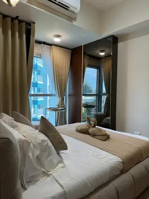 a bedroom with a large white bed with windows at Stylish 1BR Near Airport Facing the Bay - 7b in Manila