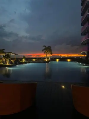 a large swimming pool at night with a palm tree at Stylish 1BR Near Airport Facing the Bay - 7b in Manila