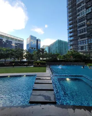 two swimming pools in a city with tall buildings at Staycations Up Above 17 at BGC in Manila