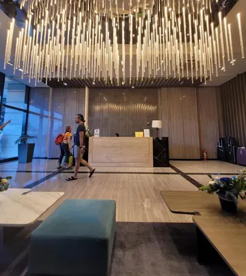a lobby with people walking in a room with chandeliers at Staycations Up Above 17 at BGC in Manila