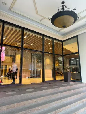 a building with glass windows and a person walking in front at Staycations Up Above 13 at BGC in Manila