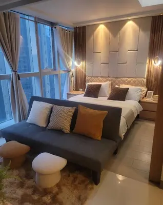 a bedroom with a bed and a couch and a window at Staycations Up Above 13 at BGC in Manila