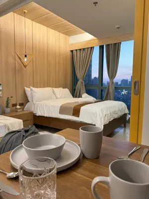 a hotel room with two beds and a table with cups at One Uptown Residences at BGC - Staycations Up Above 15 in Manila