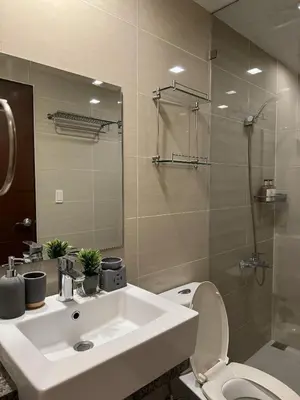 a bathroom with a sink and a toilet and a shower at One Uptown Residences at BGC - Staycations Up Above 15 in Manila