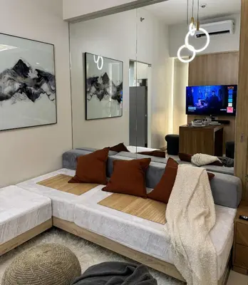 a living room with a large bed and a tv at One Uptown Residences at BGC - Staycations Up Above 15 in Manila