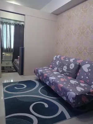 a living room with a couch and a carpet at Reynas place at sea residences in Manila