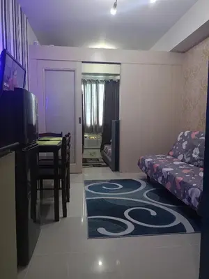 a living room with a couch a table and a dining room at Reynas place at sea residences in Manila
