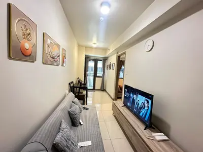 a living room with a couch and a flat screen tv at Kota S Residences in Manila