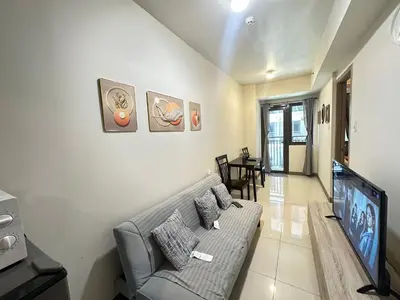 a living room with a couch and a flat screen tv at Kota S Residences in Manila