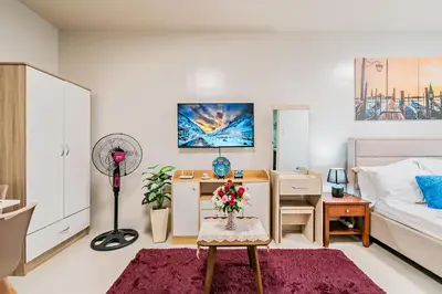 a bedroom with a bed and a desk with a fan at Precious Florannjoe in Manila