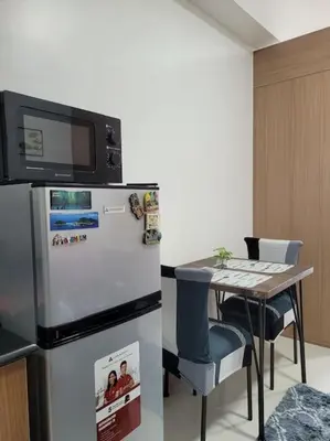 a kitchen with a refrigerator and a table with a microwave at Jireh's Staycation in Makati in Manila