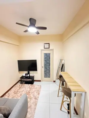 a living room with a ceiling fan and a flat screen tv at Casa Luz Budget Condotel in Manila