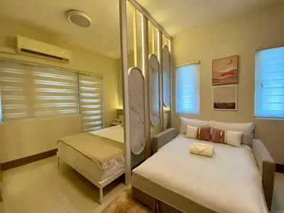 a bedroom with two beds and two windows at Casa Eleganza at Fame Residences - 1BR corner unit, CBD, Gym, Pool, WiFi, Great View in Manila