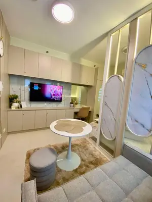 a living room with a table and a tv at Casa Eleganza at Fame Residences - 1BR corner unit, CBD, Gym, Pool, WiFi, Great View in Manila