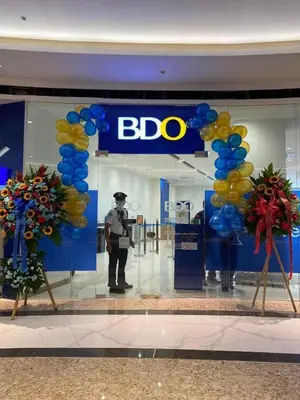 a bdo store with a man in the window with balloons at Casa Eleganza at Fame Residences - 1BR corner unit, CBD, Gym, Pool, WiFi, Great View in Manila