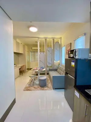 a kitchen and living room with a couch and a table at Casa Eleganza at Fame Residences - 1BR corner unit, CBD, Gym, Pool, WiFi, Great View in Manila