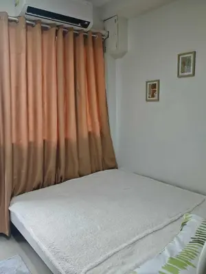 a bed in a room with an orange curtain at Zeki's Place - Shore 2 Residences MOA in Manila