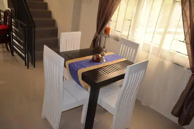 a dining room table with white chairs and a table with a table at Home in Pasig in Manila