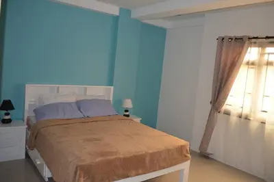 a bedroom with a bed with blue walls and a window at Home in Pasig in Manila