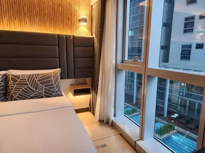 a bedroom with a bed and two large windows at BGC Cosy Hotel Vibe Uptown Parksuites Studio in Manila