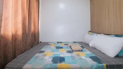 a bed with a colorful quilt and a pillow at Lascianos SMDC Shore Residences by RedDoorz in Manila