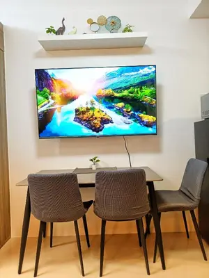a tv hanging on a wall above a table with chairs at Fame Residence Tower 1 Cozy Hotel Style 1 Bedroom with Balcony pool View in Manila