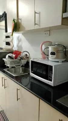 a kitchen counter with a microwave and a sink at Eriel condotel in Manila