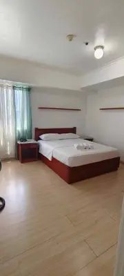 a bedroom with a large bed and a wooden floor at Elite Homestays Family-Friendly Condo Near Malls with Pool & Gym in Manila