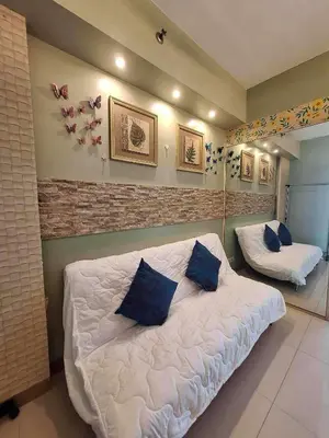 a bedroom with a bed with blue pillows on it at Oasis MOA- Sea Residences in Manila