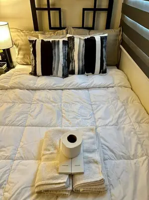 a white bed with a roll of toilet paper on it at Luxury Style Living-Netflix Ready in Manila
