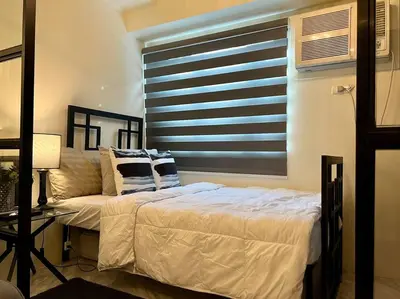 a bed and a couch in a room with a window at Luxury Style Living-Netflix Ready in Manila