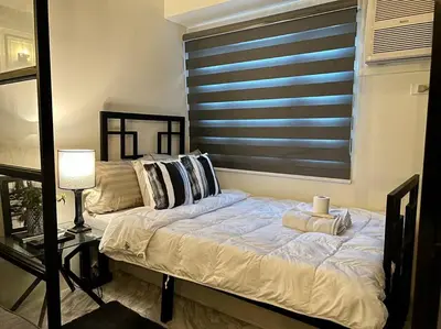 a bedroom with a bed with pillows and a window at Luxury Style Living-Netflix Ready in Manila
