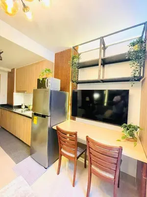 a kitchen with a table and a stainless steel refrigerator at Alonas Residences in Manila