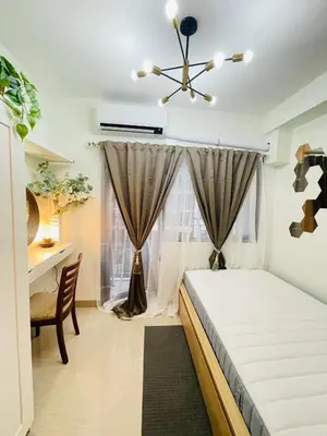 a bedroom with a bed and a desk and a window at Alonas Residences in Manila