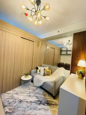 a living room with a couch and a chandelier at Alonas Residences in Manila