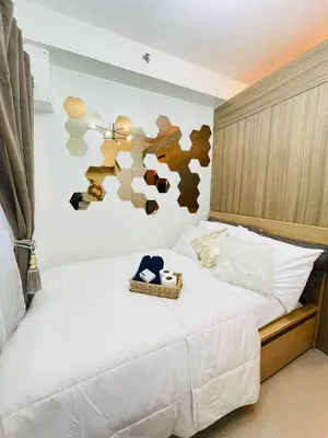 a bedroom with a white bed with a hat on it at Alonas Residences in Manila
