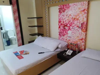 a bedroom with two beds and a phone on a table at Hotel Sogo - EDSA, Pasay Harrison in Manila