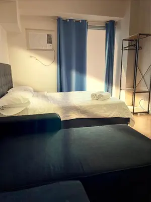 a bedroom with two beds and a window with blue curtains at 8 Adriatico Homestay - S in Manila