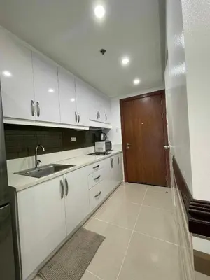 a kitchen with white cabinets and a sink and a door at YAM's WANDERLUST in Manila