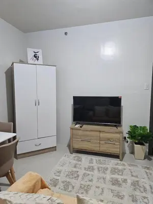 a living room with a flat screen tv and a cabinet at 5F J Phase1 Sevilla in Manila