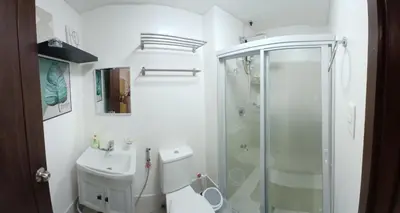 a bathroom with a shower and a toilet and a sink at Covent Garden South Residences in Manila