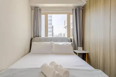 a bedroom with a bed with white sheets and a window at Luxury Bayview Condo MOA & PICC Free WiFi in Manila