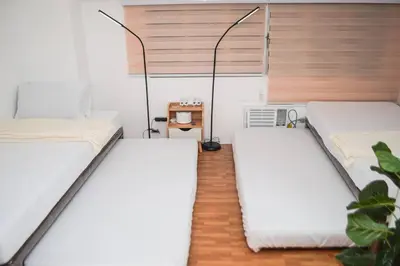 two beds in a room with white walls at Metro Stay - Prime Spot Near Malls & Major Cities in Manila