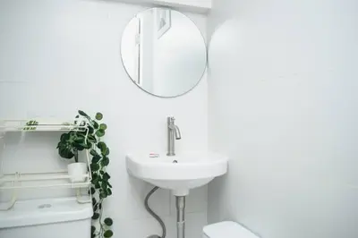 a white bathroom with a sink and a mirror at Metro Stay - Prime Spot Near Malls & Major Cities in Manila