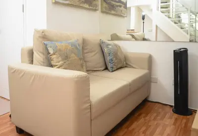 a white couch with pillows sitting in a living room at Metro Stay - Prime Spot Near Malls & Major Cities in Manila