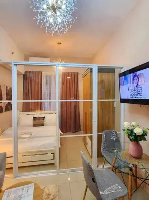 a bedroom with a bed and a tv and a table at Payapa Staycation by DC in Manila