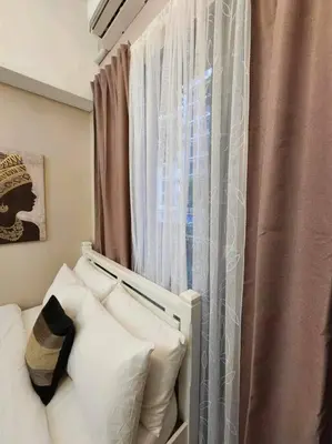 a room with a window with a couch and a curtain at Payapa Staycation by DC in Manila