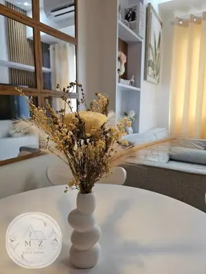 a white vase with dried flowers on a table at MZ Suite Home at SMDC Charm Residences in Manila