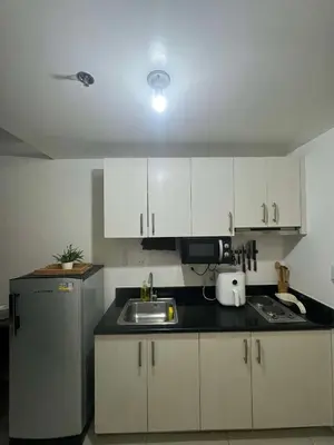 a kitchen with white cabinets and a sink and a refrigerator at Makati Jazz Staycation in Manila