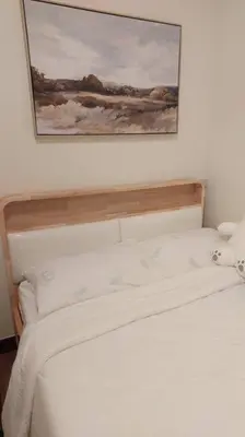 a bedroom with a white bed with a picture on the wall at Helaena's Scandi Haven in Manila